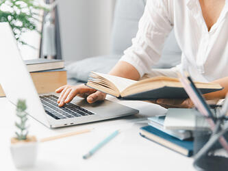 person using laptop and notebook at desk